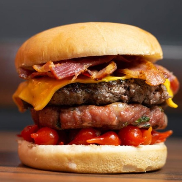 Lanche alto com queijo, bacon e camadas generosas de recheio